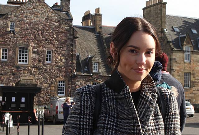 Portrait of Larissa in front of a stone building